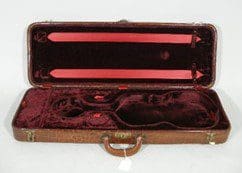 An open vintage violin case with dark red interior.